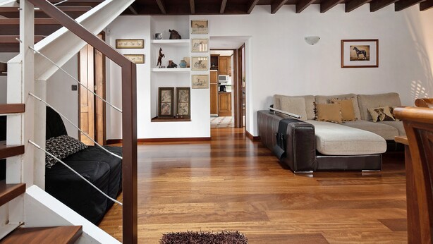Un salon moderne avec un escalier en bois, un ensemble de canapés et une bibliothèque agrémentée de cadres avec des photos.