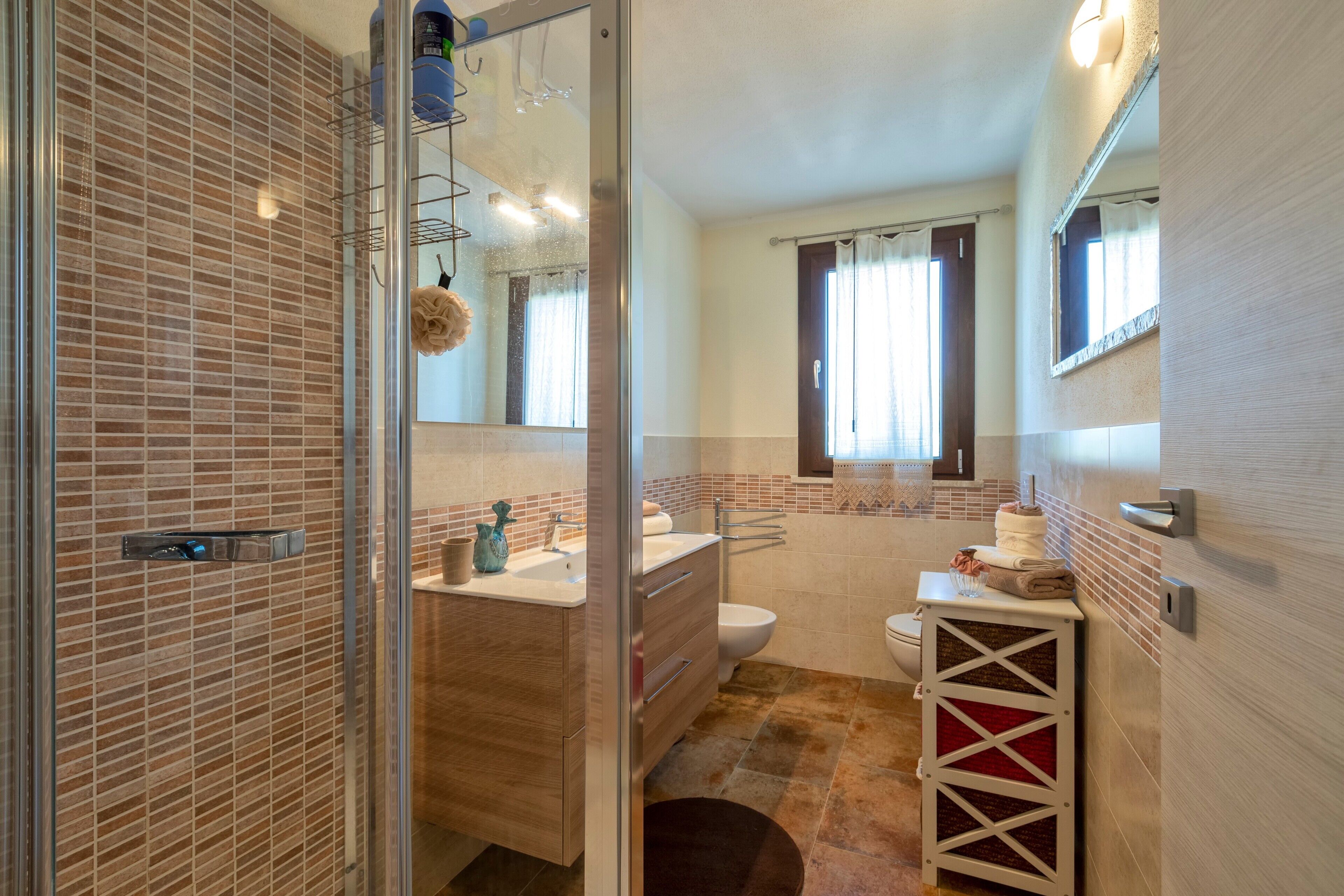 Un bagno completo di doccia, lavandino, WC e specchio.