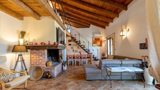 A spacious living area with a fireplace, a staircase, and a sofa. - Holiday Home 'La Casa di Valverde' with Garden & A/C (Alghero)