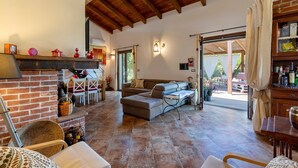 A spacious living area with a fireplace, a sofa, and a dining table. - Holiday Home 'La Casa di Valverde' with Garden & A/C (Alghero)