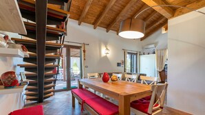 A dining area with a wooden table and benches, a staircase, and a kitchen in the background. - Holiday Home 'La Casa di Valverde' with Garden & A/C (Alghero)