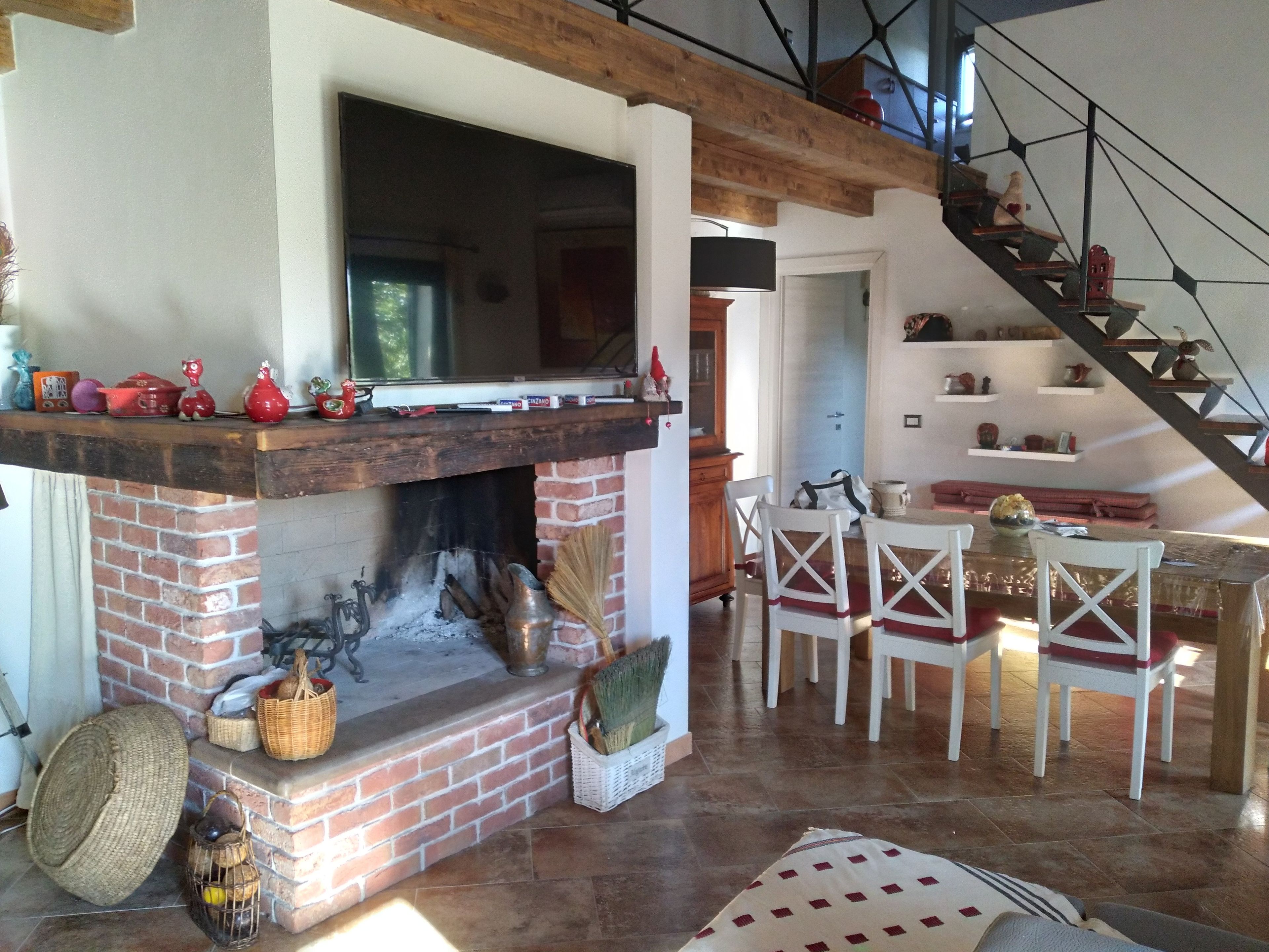 Un saló acollidor amb una llar de foc, una zona de menjador i una escala.