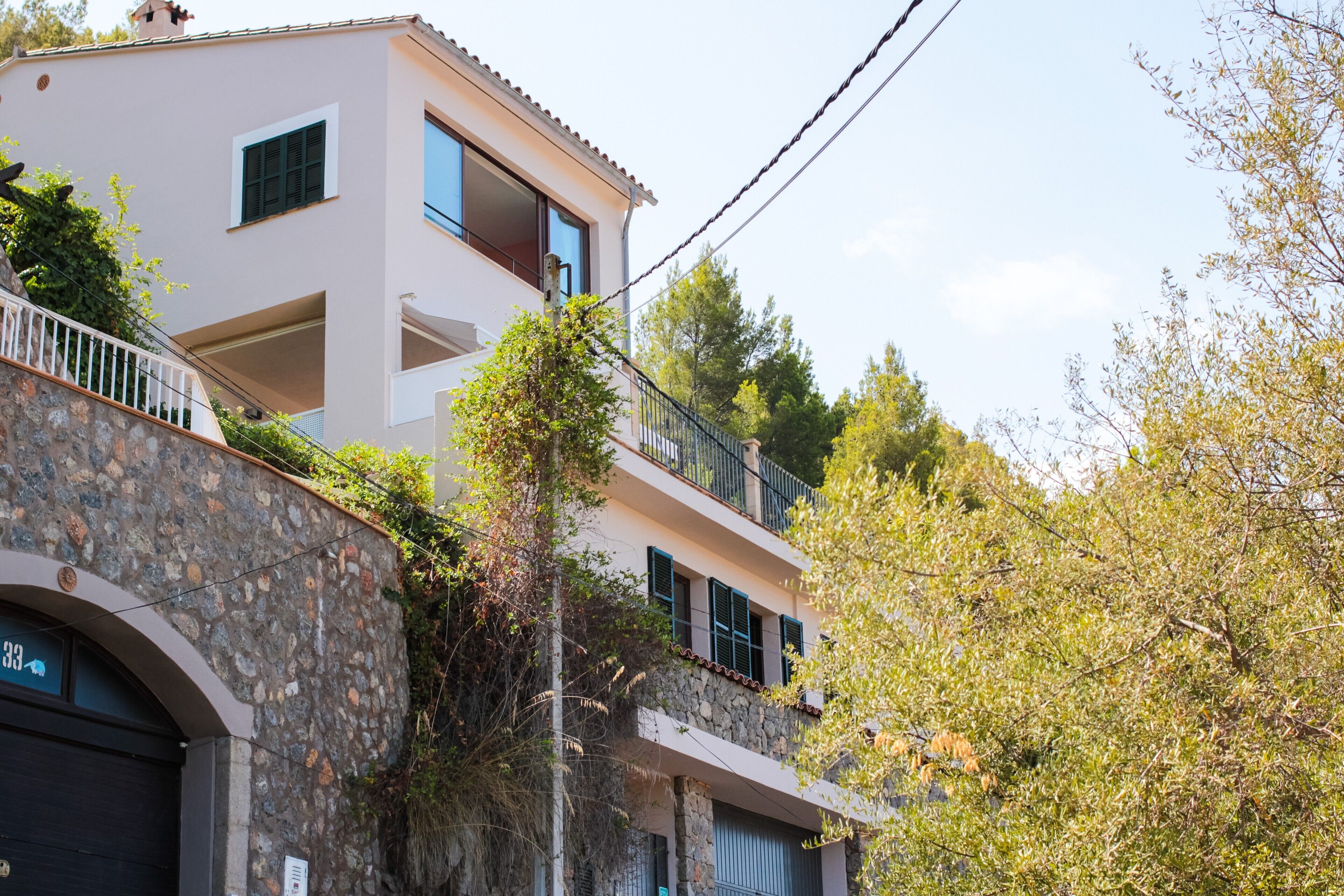 Un edificio de varios pisos con fachada de piedra, balcones y cielo despejado.