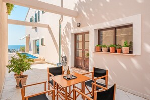 A patio with a table and chairs, a pool, and potted plants.