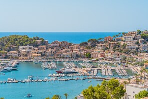 Un pueblo costero con un puerto deportivo lleno de barcos, edificios con balcones y una vista despejada del mar.