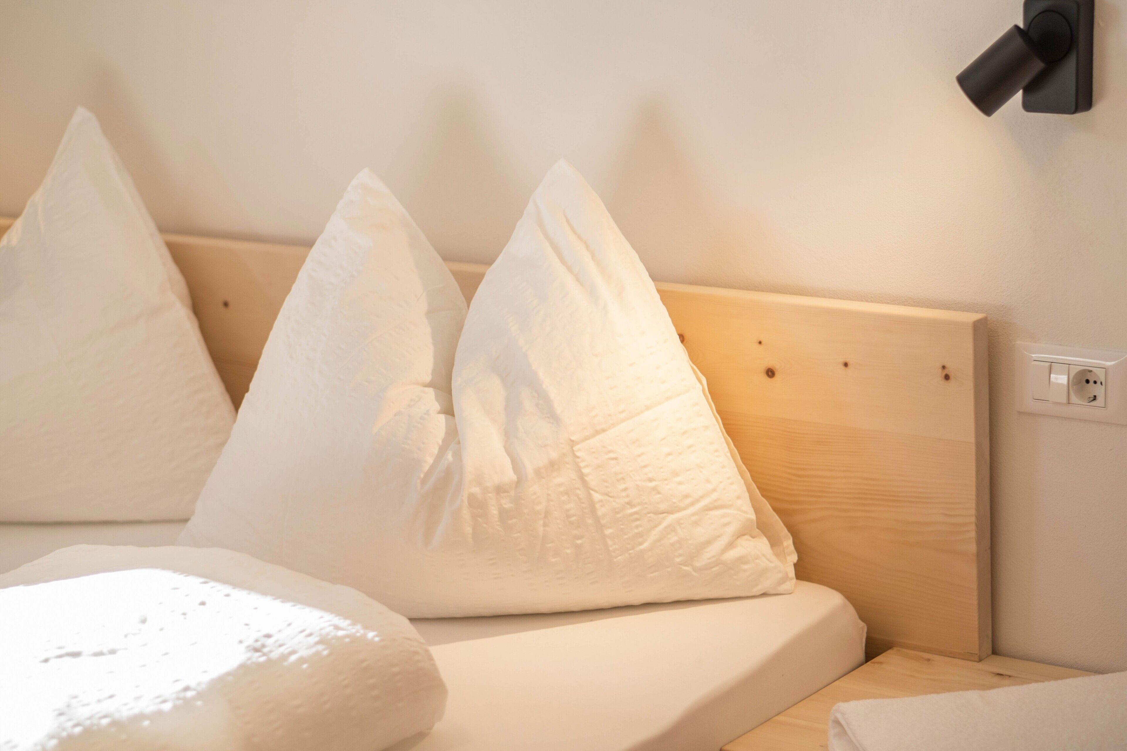 Ein Bett mit weißen Kissen und einem Holzkopfteil.