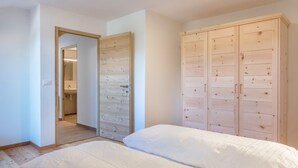 A bedroom with a wooden wardrobe, a bed with white bedding, and a wooden floor. - Holiday Apartment 'Nigglhof Katarina' with Mountain View, Balcony & Wi-Fi (redagno)