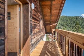 Une cabane en bois dotée d’un balcon donnant sur une zone boisée.