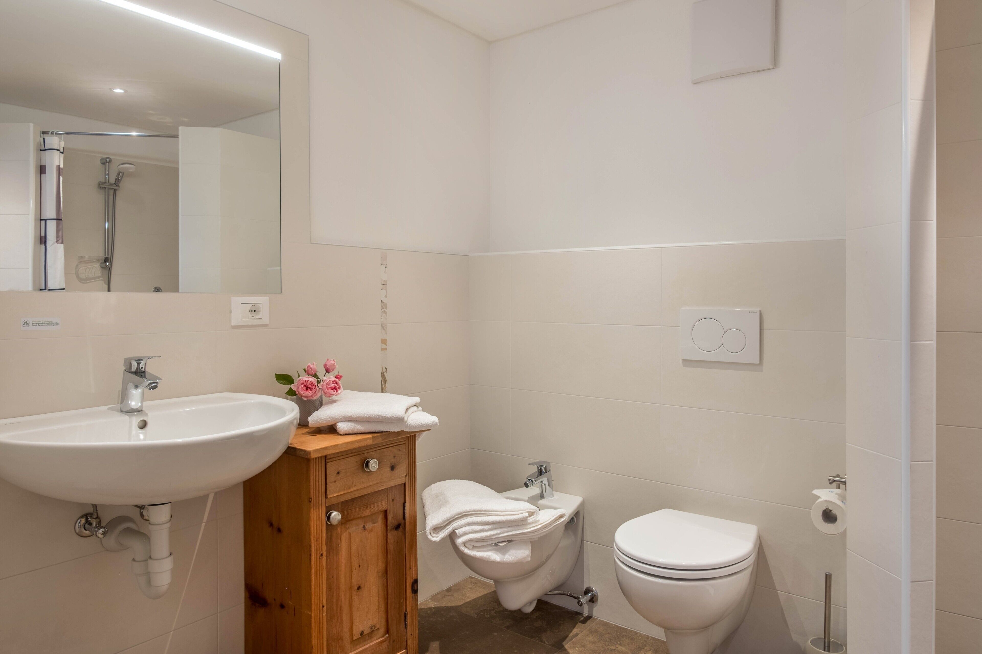A bathroom with a sink, mirror, toilet, and shower.