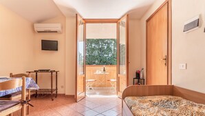 A bedroom with a bed, a desk, a chair, a TV, and an open door leading to a balcony. - San Carlo Holiday Home near the Beach with Balcony (Campofelice di Roccella)