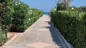 A paved pathway with a hedge on one side and a clear blue sky in the background. - San Carlo Holiday Home near the Beach with Balcony (Campofelice di Roccella)