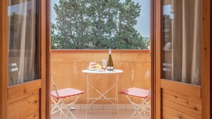 A balcony with a table, two chairs, and a bottle of wine. - San Carlo Holiday Home near the Beach with Balcony (Campofelice di Roccella)