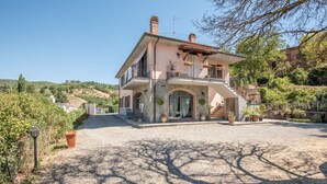 A two-story house with a balcony, a gravel driveway, and surrounding greenery. - 'Casa Vacanze Chianti Summer' with Pool, Garden & Wi-Fi (Gaiole in Chianti)