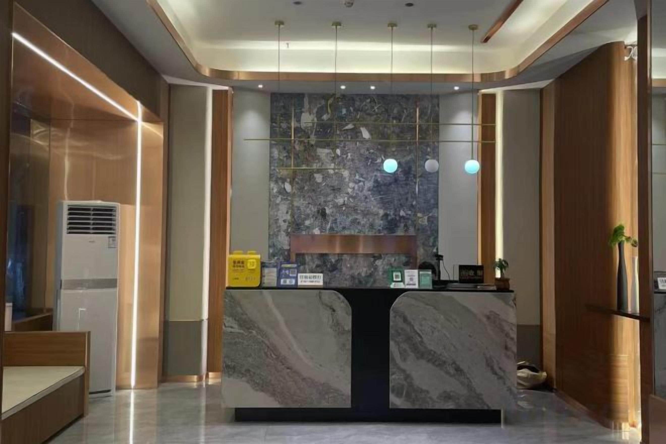 A reception desk with a marble top, a wall-mounted clock, and a small plant on the right.