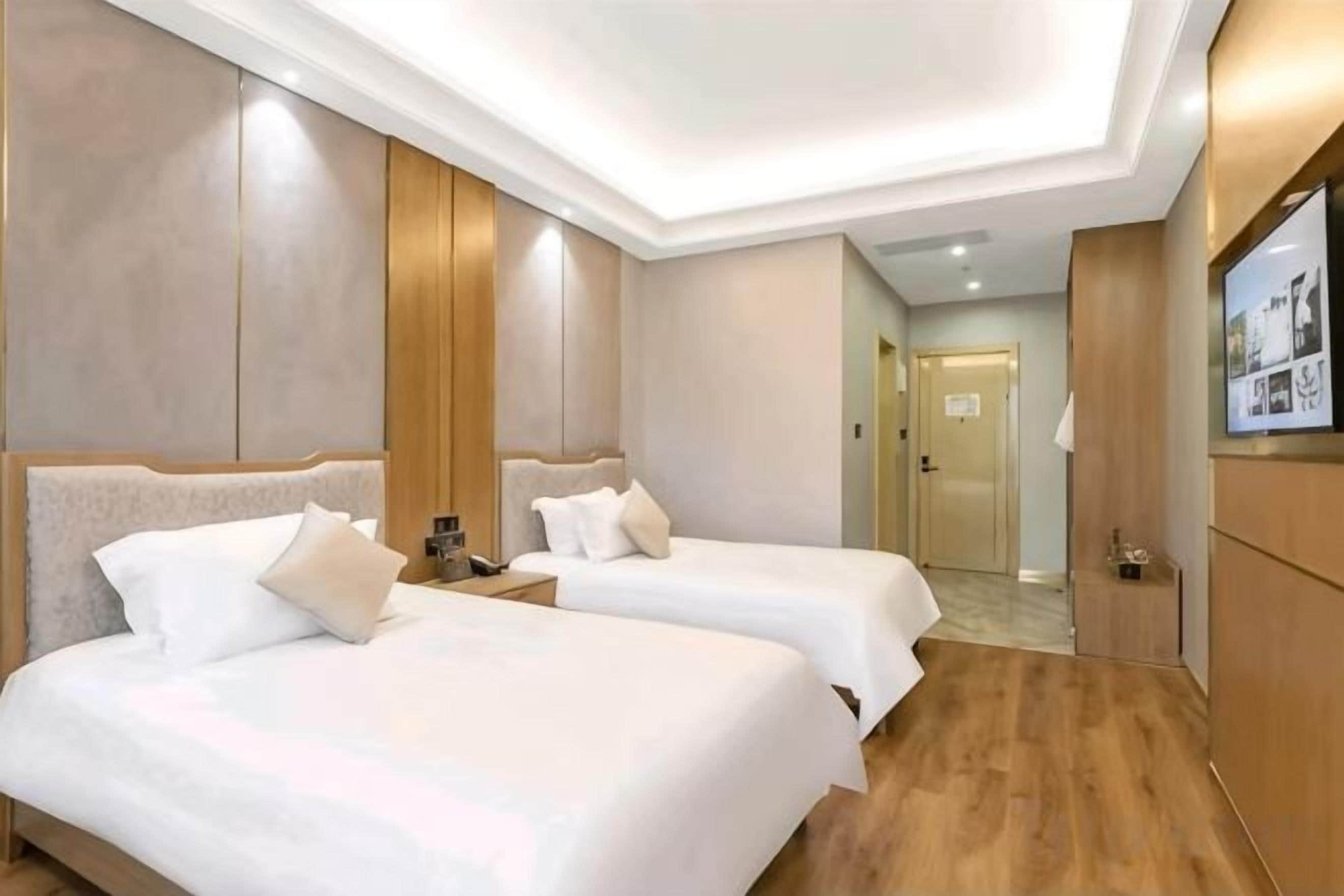 Una habitación de hotel con dos camas, televisión y suelo de madera.