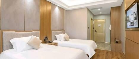 Una habitación de hotel con dos camas, televisión y suelo de madera.