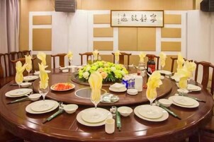 A round dining table set for a meal with plates, glasses, and a centerpiece of flowers.