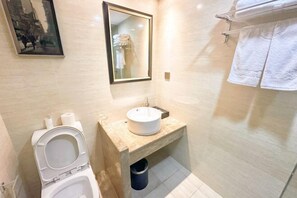 A bathroom with a toilet, sink, mirror, and towel rack. - Hailian Xianggan Hotel (Yongxin)