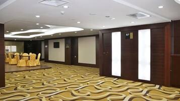 A conference room with a patterned carpet, round tables with chairs, and a large screen.