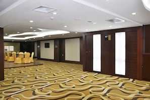A conference room with a patterned carpet, round tables with chairs, and a large screen. - Hailian Xianggan Hotel (Yongxin)