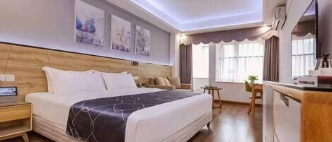 Ein Hotelzimmer mit einem großen Bett, einem Schreibtisch mit Stuhl, einem Fernseher und einem Fenster mit Vorhängen.