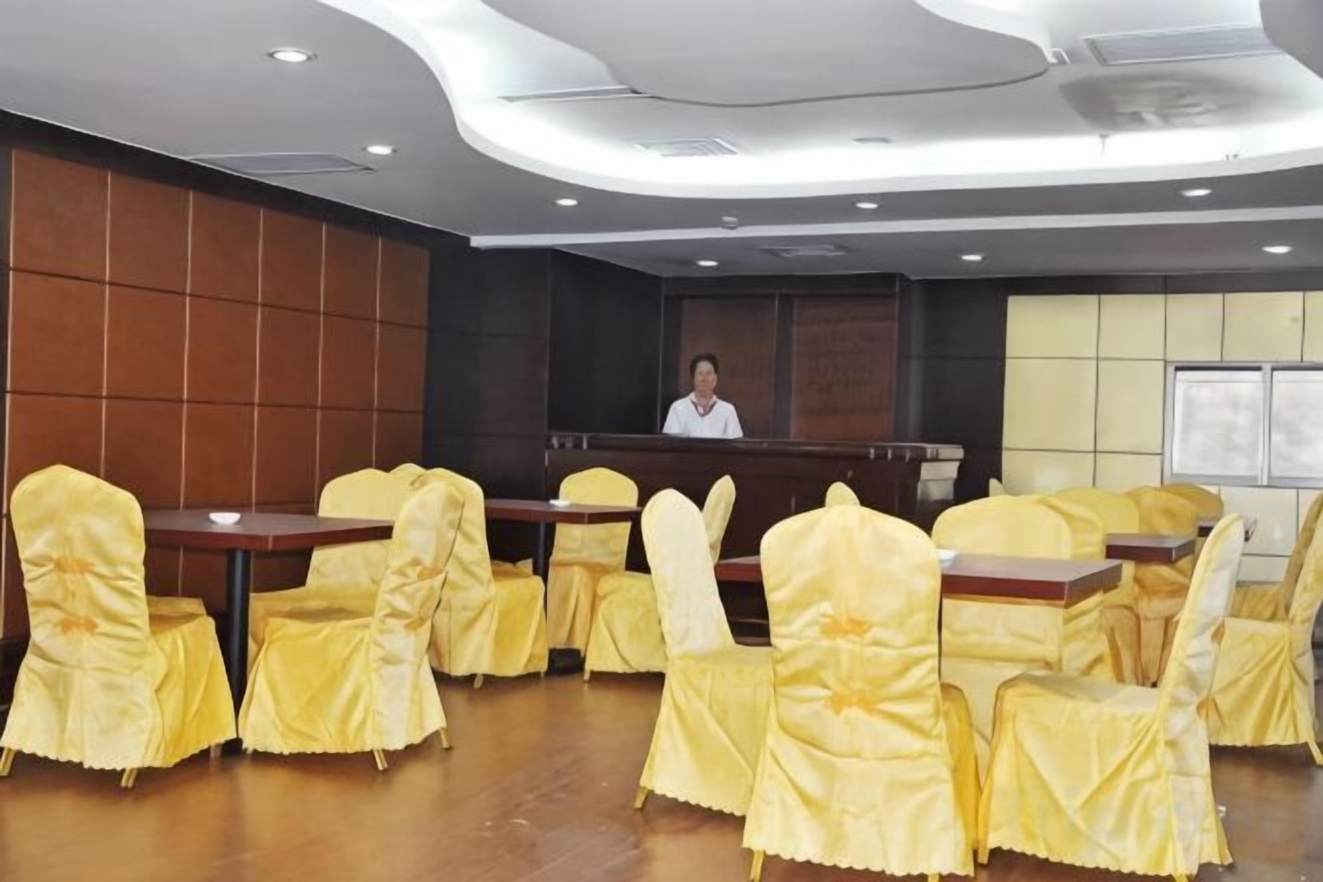 A conference room with tables and chairs, a reception desk, and a person standing at the desk.