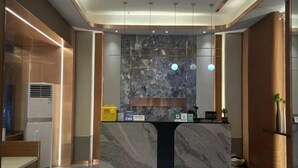 Un mostrador de recepción con encimera de mármol, pared con textura y diseño moderno del techo.