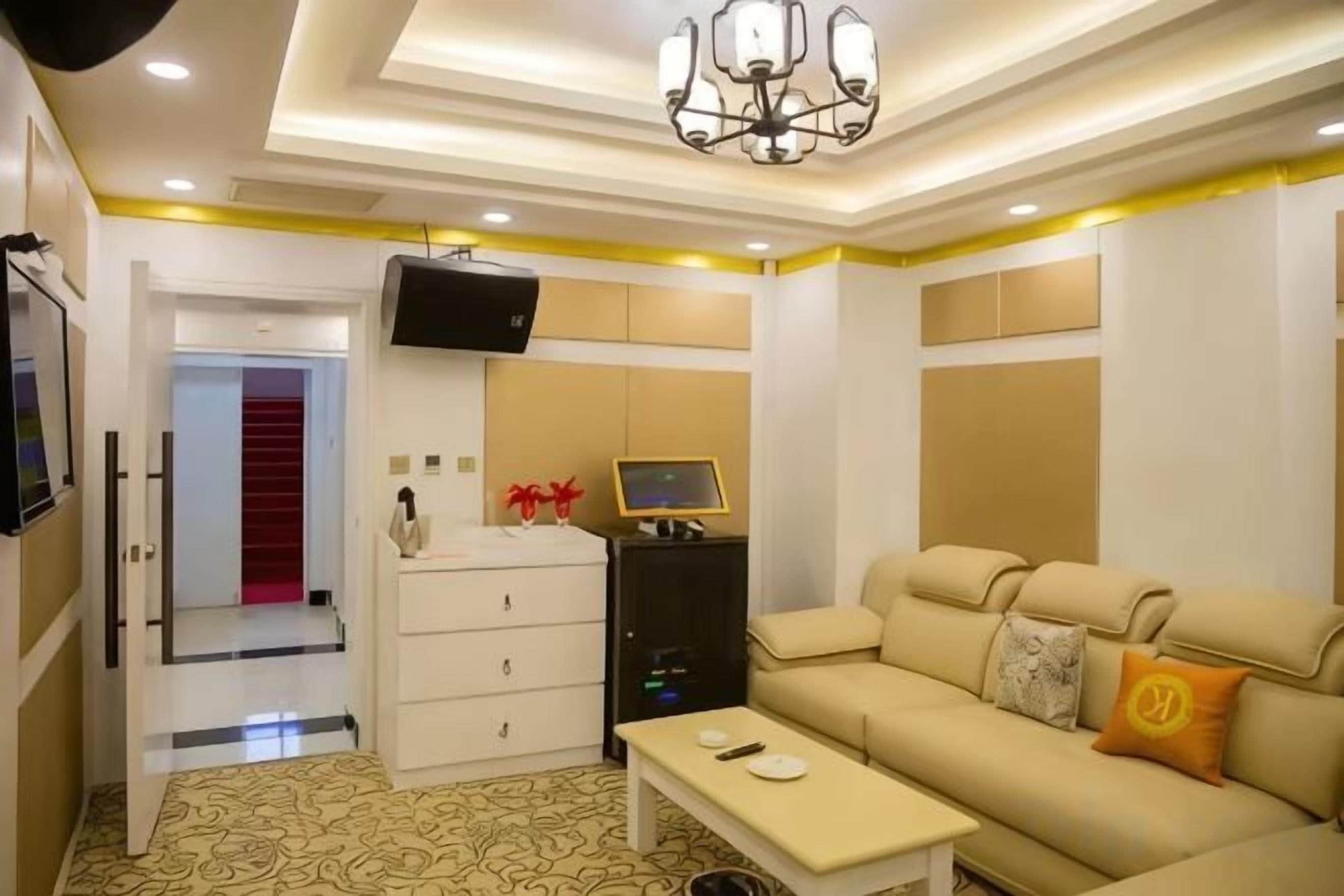Quarto de hotel com sofá, televisão, escrivaninha e guarda-roupa.