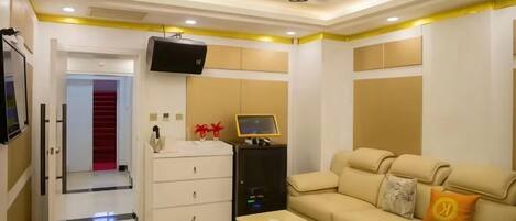 Quarto de hotel com sofá, televisão, escrivaninha e guarda-roupa.