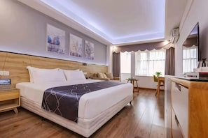 A hotel room with a bed, bedside table, and a desk with a chair.
