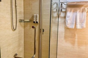 A bathroom with a glass shower enclosure, a handheld showerhead, and a towel rack with towels. - Hailian Xianggan Hotel (Yongxin)