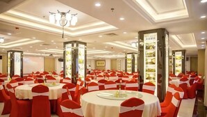 Un salón de banquetes con mesas redondas y sillas rojas, que destaca por un diseño de techo moderno y pilares iluminados.