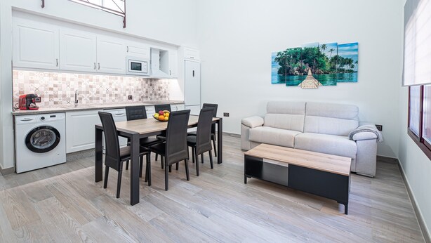 Un espacio habitable compacto con kitchenette, comedor y sofá.
