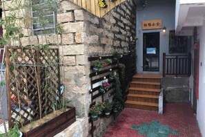 Un edificio de piedra con una escalera de madera que conduce a una puerta con la inscripción '小倉'.