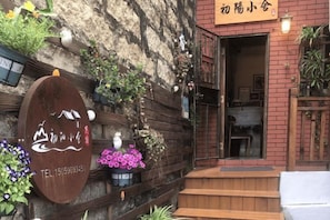 Un edificio rústico con fachada de madera, un letrero con caracteres chinos y una entrada pequeña.