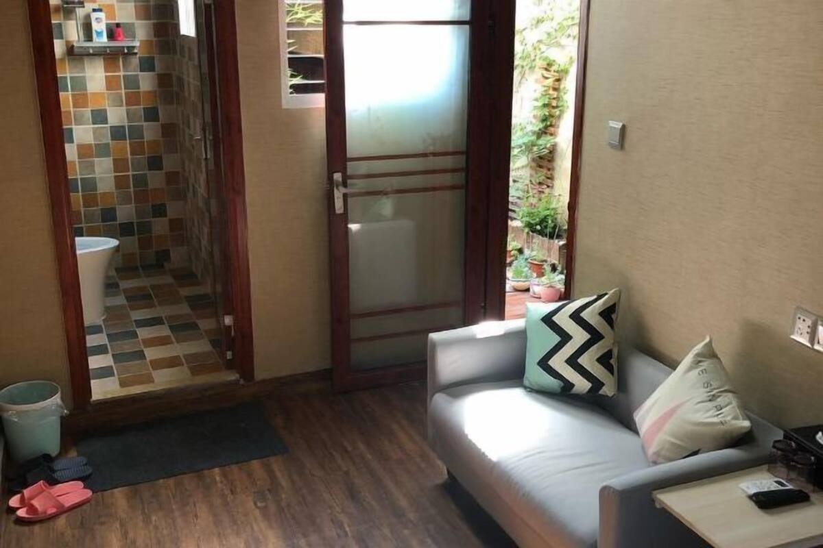 Una habitación pequeña y acogedora con un sofá, una mesita de centro y vistas a un baño con azulejos.