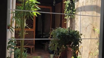 A traditional Japanese entrance with a wooden door, a small garden area with plants, and a tiled floor.