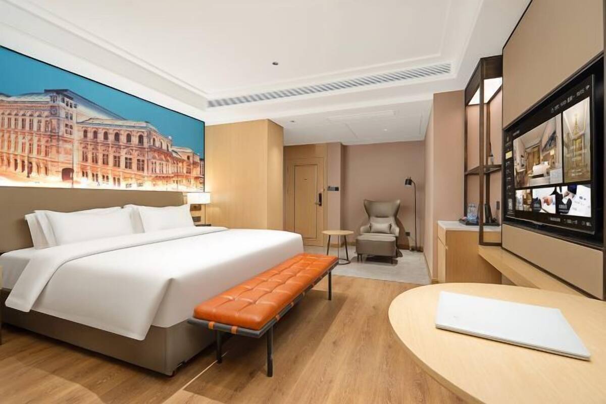 Une chambre d’hôtel avec un grand lit, un banc, un bureau et une télévision.
