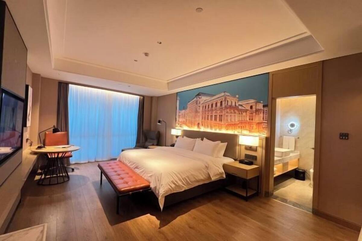 Une chambre d’hôtel moderne, dotée d’un grand lit, de tables de chevet, d’un bureau et d’une chaise.