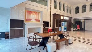 A spacious lobby with a long wooden table and benches, a fireplace, and a large painting. - Vienna International Hotel · Yonghe Branch, Wuli Industrial Zone, Quanzhou South Railway Station (Jinjiang)