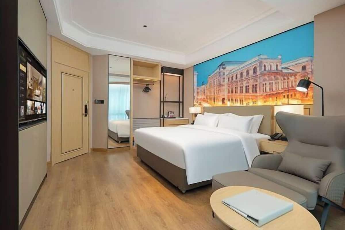 Une chambre d’hôtel avec un lit, un canapé, un bureau, une lampe et un tableau au mur.