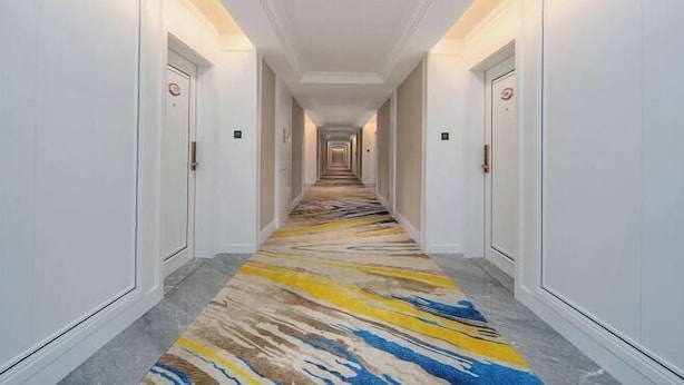 A hotel hallway with a patterned carpet, white walls, and doors on both sides. - Vienna International Hotel · Yonghe Branch, Wuli Industrial Zone, Quanzhou South Railway Station (Jinjiang)
