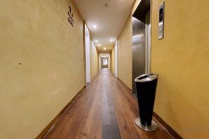 Un long couloir étroit, doté d’un plancher en bois et d’une poubelle placée sur le côté droit.