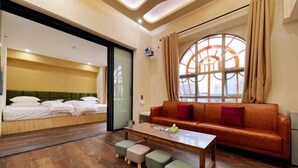 Ein Zimmer mit einem Bett, einem Schlafsofa, einem Couchtisch und einem Fenster mit Vorhängen.
