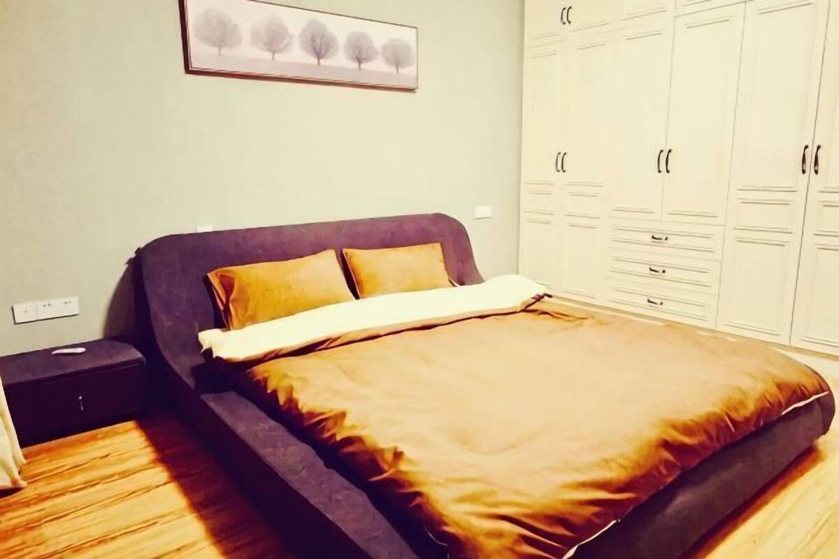 Un dormitorio con cama, mesita de noche, armario y un cuadro en la pared.