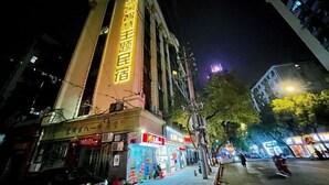Ein Gebäude mit beleuchteter Beschilderung, eine Straße mit Geschäften und ein klarer Nachthimmel.