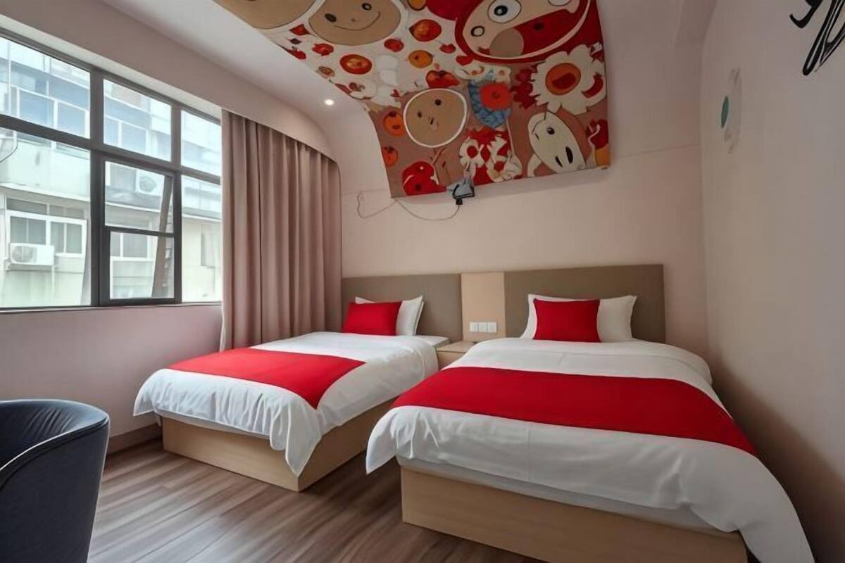 Habitación de hotel con dos camas, una ventana y un mural en el techo.