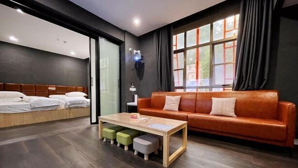 Ein modernes Hotelzimmer mit einem Bett, einem Schlafsofa, einem Couchtisch und einem fenster mit Vorhängen.