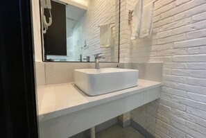 Ein modernes Badezimmer mit einem weißen Waschbecken, einem großen Spiegel und einer weißen Ziegelwand.
