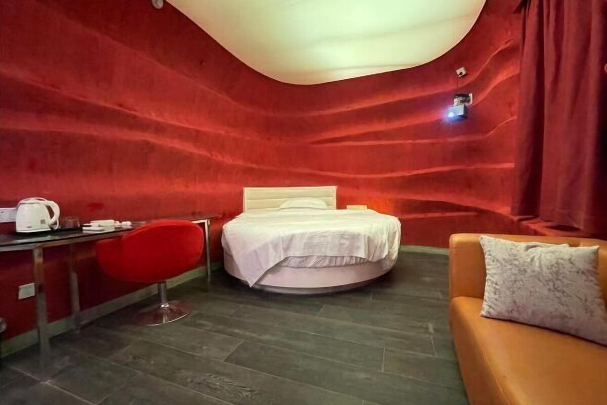 Ein Zimmer mit einem Bett, einem Schreibtisch, einem roten Sessel und einer Couch.